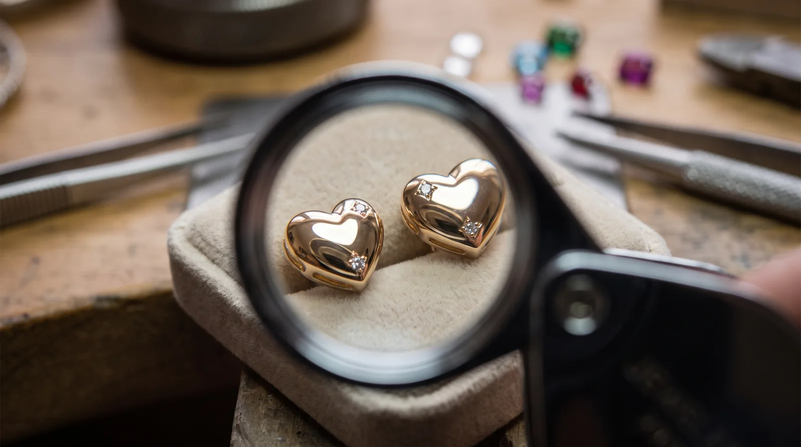 Rolex heart earrings displayed with a jeweler's loupe highlighting quality details before buying