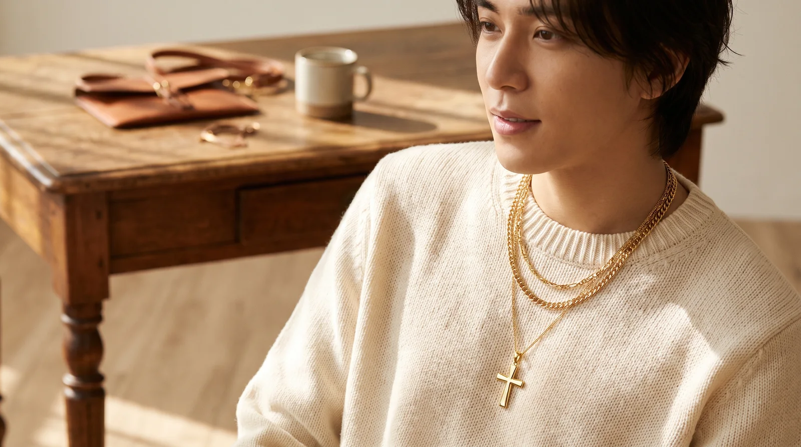 Gold cross pendant positioned at different neckline lengths